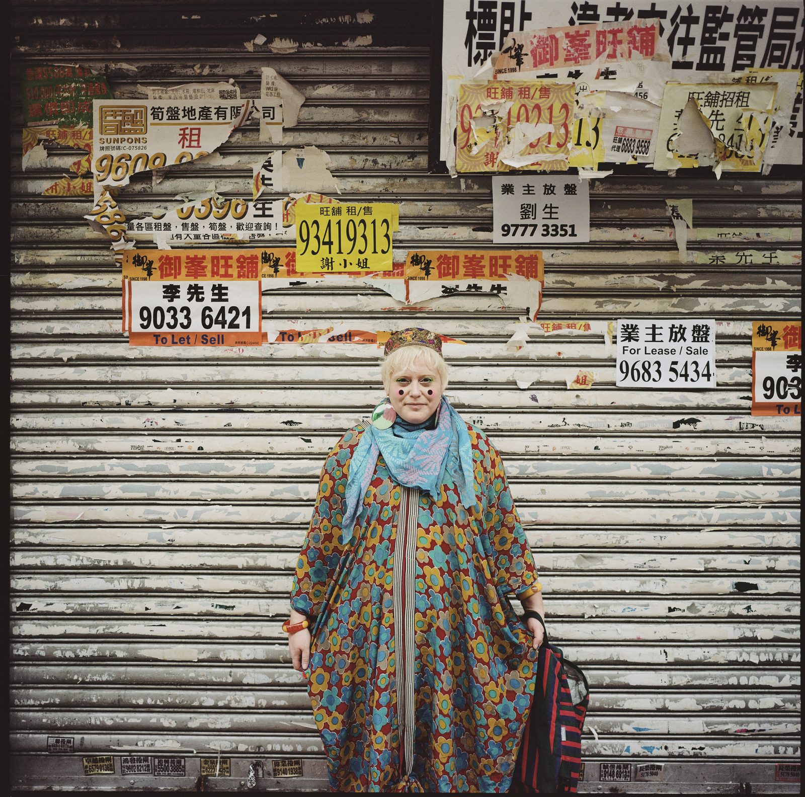 Bethan Laura Wood in front of a poster-covered shutter, Hong Kong